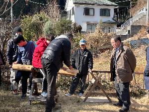 大人と小学生が一緒になって丸太を切る様子