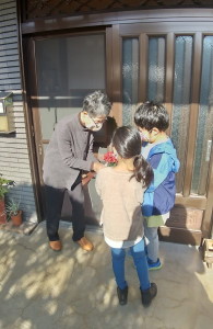 女の子と男の子が女性に花を渡している写真