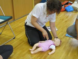 乳幼児の人形を使い、誤飲除去、心肺蘇生法を教わりながら実践を行っている参加者の写真
