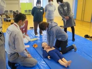 人形を使い救急隊員の方から心臓マッサージの技法を教わっている様子の研修参加者の写真
